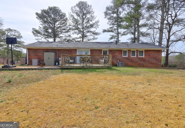 back of property with a deck, a yard, brick siding, and cooling unit