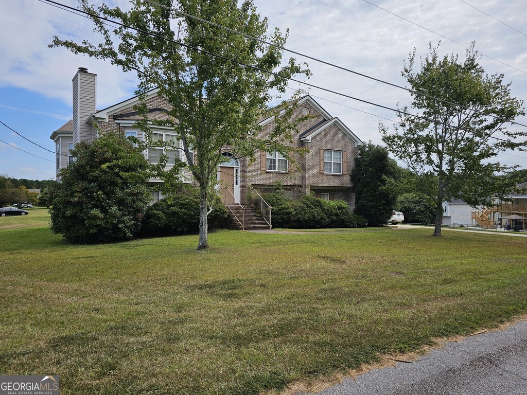 view of front facade with brick siding, a chimney, and a front yard