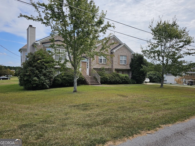 view of front facade with brick siding, a chimney, and a front yard