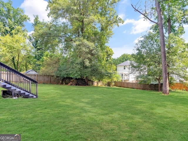 view of yard featuring stairs and a fenced backyard