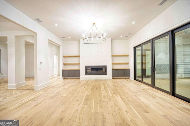 unfurnished living room featuring a glass covered fireplace, visible vents, light wood-style flooring, and baseboards