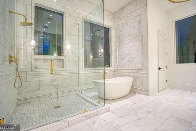 full bath featuring marble finish floor, a freestanding tub, a shower stall, and baseboards