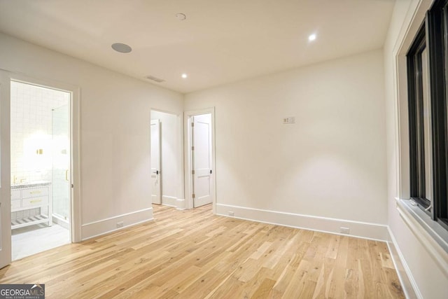 empty room with light wood-type flooring, baseboards, and recessed lighting