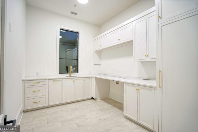 interior space with white cabinetry, visible vents, light countertops, and a sink