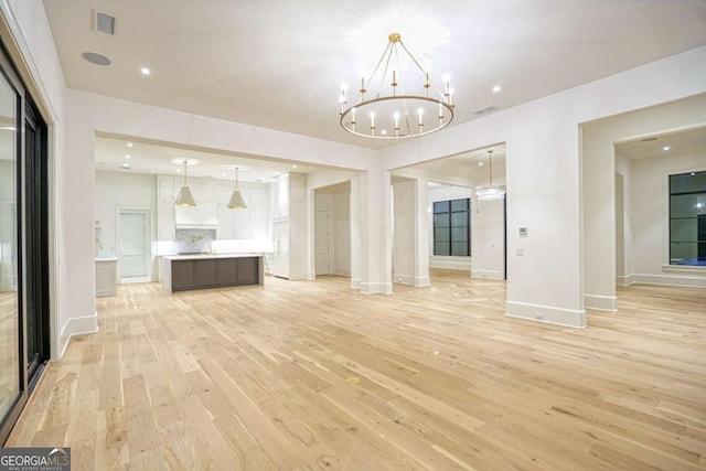 unfurnished living room with recessed lighting, visible vents, light wood-style floors, a chandelier, and baseboards