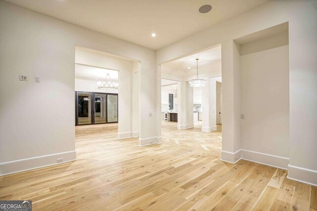 unfurnished room with light wood finished floors, baseboards, a notable chandelier, and recessed lighting