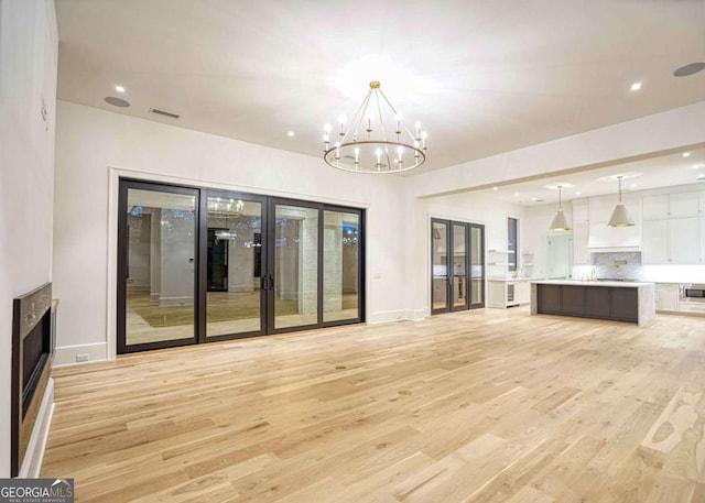 unfurnished living room with light wood-style flooring, recessed lighting, visible vents, french doors, and an inviting chandelier