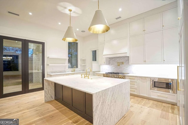 kitchen featuring open shelves, appliances with stainless steel finishes, white cabinetry, a sink, and light stone countertops