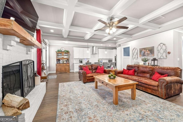 living area featuring a large fireplace, dark wood finished floors, coffered ceiling, ceiling fan, and beamed ceiling