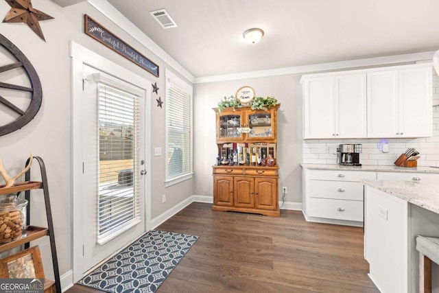 doorway to outside featuring crown molding, dark wood-type flooring, visible vents, and baseboards