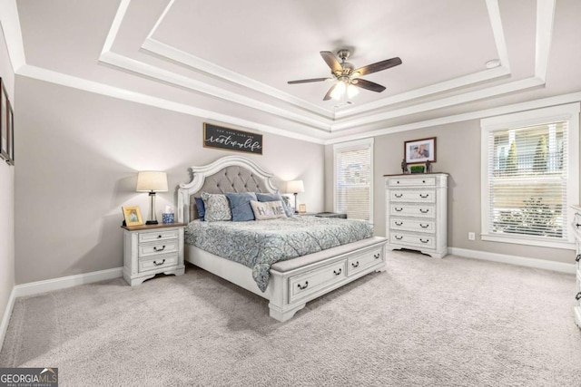 bedroom featuring light carpet, a raised ceiling, and baseboards