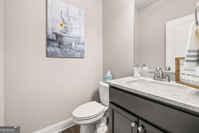 bathroom with baseboards, vanity, toilet, and wood finished floors