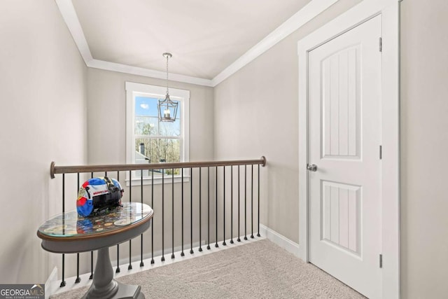 hallway featuring crown molding, carpet, baseboards, and a notable chandelier