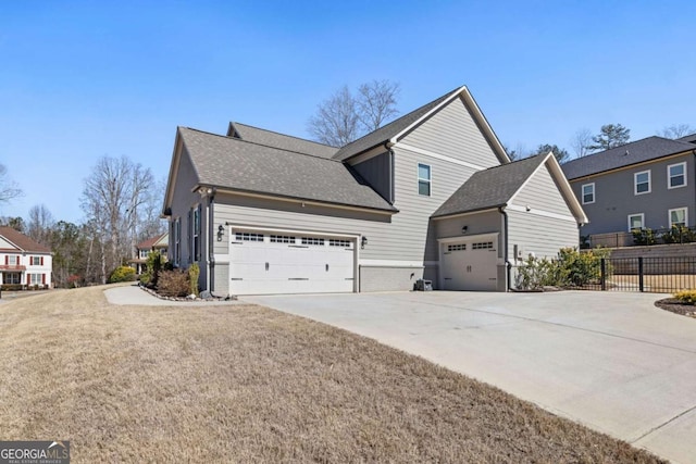 view of front facade featuring a garage, a shingled roof, concrete driveway, fence, and a front yard