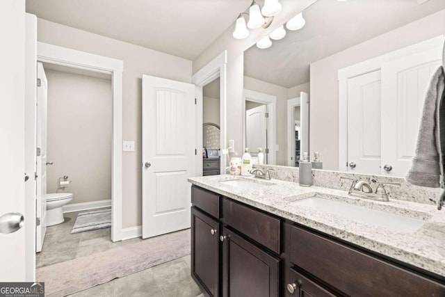 full bath featuring double vanity, baseboards, toilet, and a sink