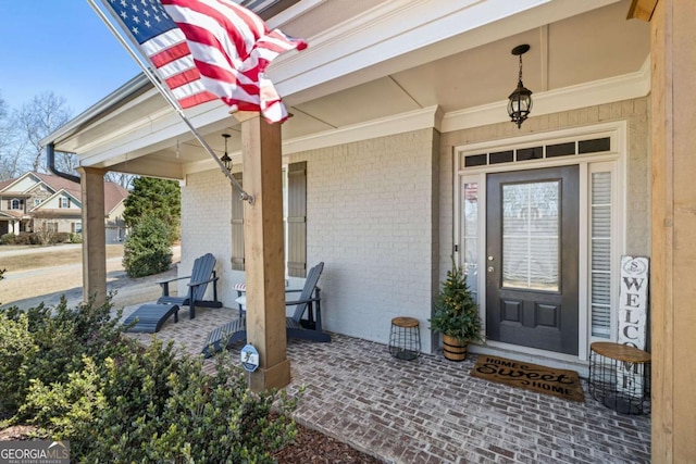 entrance to property featuring a porch and brick siding