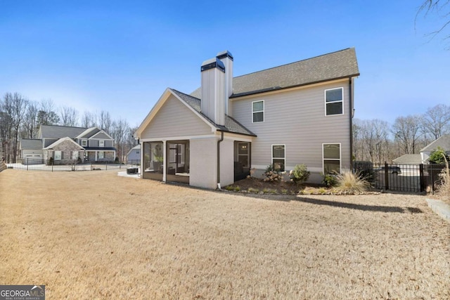 rear view of property featuring brick siding, fence, a sunroom, a yard, and a chimney