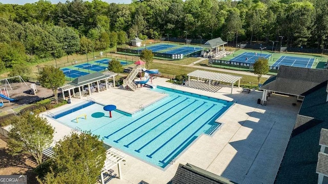 community pool with a tennis court, a water slide, fence, and a pergola