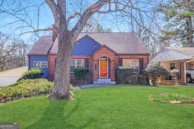 view of front of home featuring roof with shingles, a front yard, a chimney, and brick siding