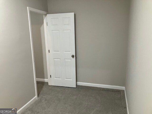 unfurnished room with dark colored carpet and baseboards