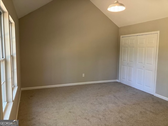 unfurnished bedroom with high vaulted ceiling, carpet, a closet, and baseboards