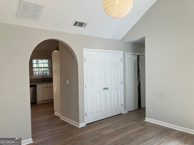 hallway with dark wood finished floors, visible vents, arched walkways, and a sink