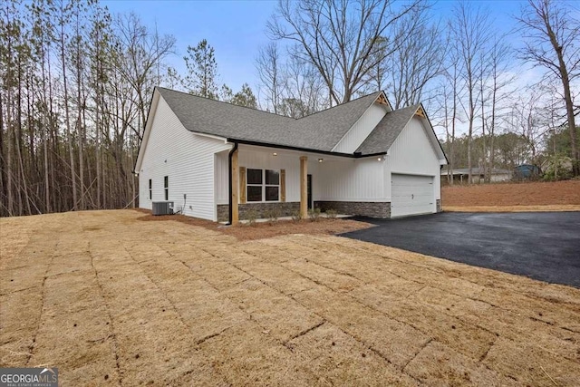 view of front facade featuring a garage, stone siding, a shingled roof, and aphalt driveway