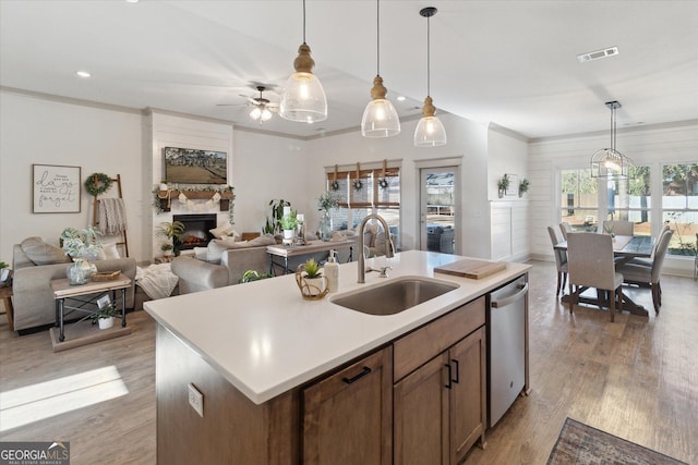 kitchen featuring light countertops, visible vents, stainless steel dishwasher, open floor plan, and a sink