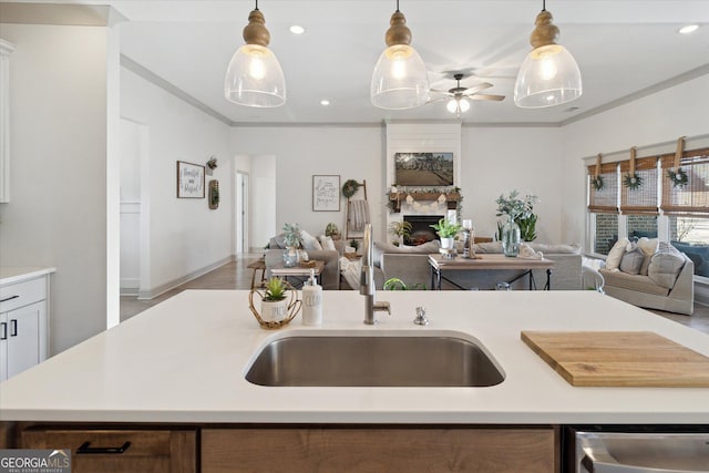 kitchen featuring a large fireplace, a sink, open floor plan, light countertops, and pendant lighting