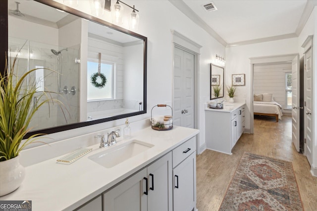 bathroom featuring connected bathroom, wood finished floors, a sink, visible vents, and a marble finish shower