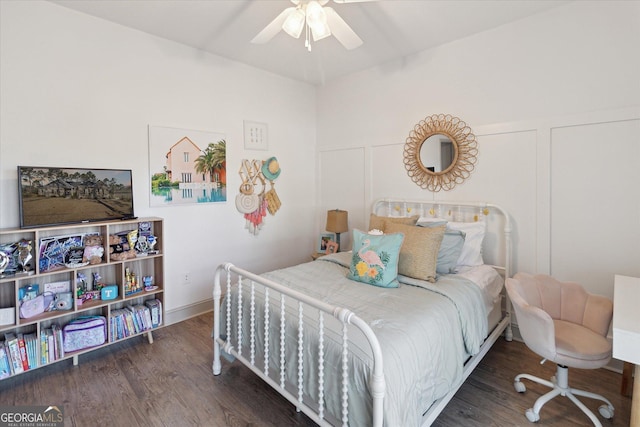 bedroom with dark wood-style floors, a decorative wall, and a ceiling fan