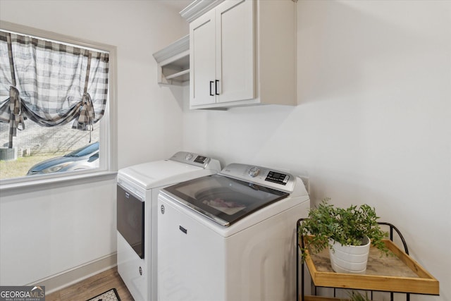 clothes washing area featuring washer and clothes dryer, wood finished floors, cabinet space, and baseboards