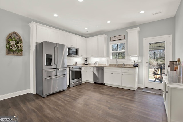 kitchen featuring stainless steel appliances, visible vents, decorative backsplash, and dark wood-style floors