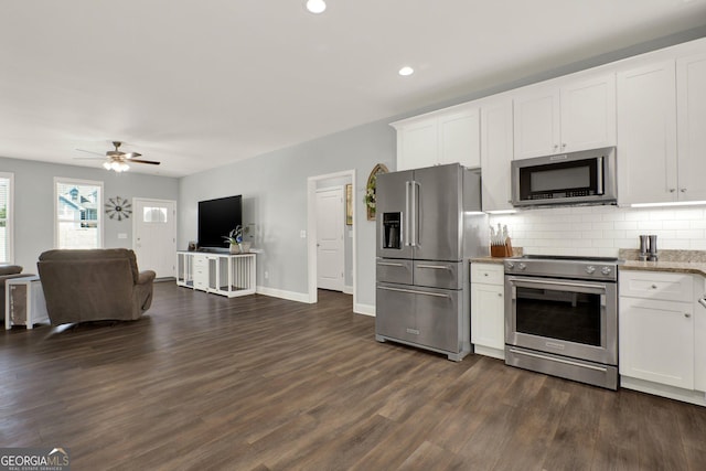 kitchen with appliances with stainless steel finishes, open floor plan, white cabinetry, and backsplash