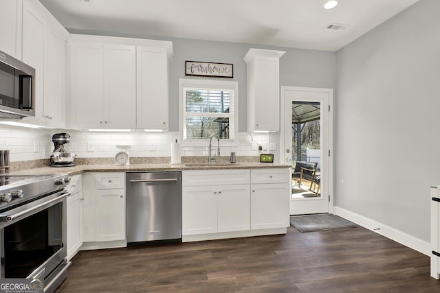 kitchen featuring tasteful backsplash, light stone counters, stainless steel appliances, white cabinetry, and a sink