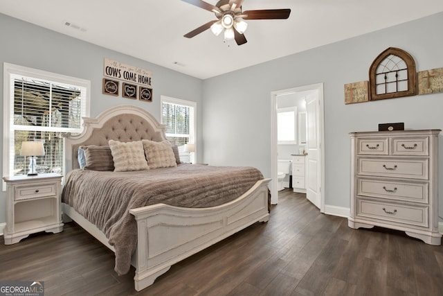 bedroom featuring dark wood finished floors, visible vents, ensuite bathroom, a ceiling fan, and baseboards