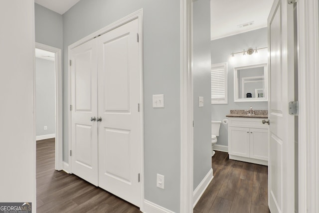 hallway featuring dark wood-style floors, visible vents, and baseboards