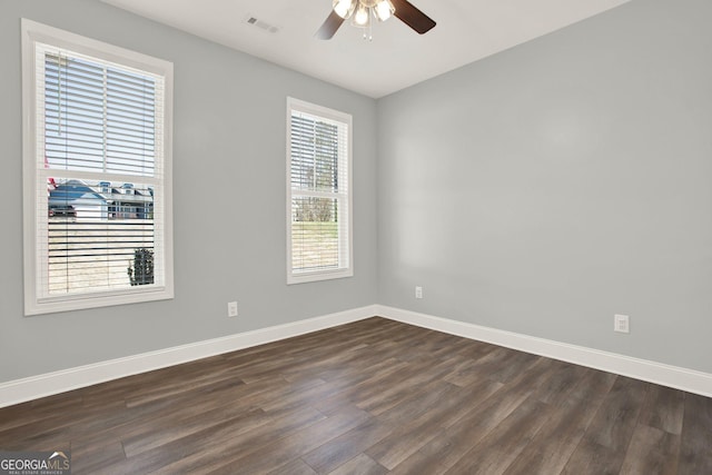 empty room with dark wood finished floors, a ceiling fan, and baseboards