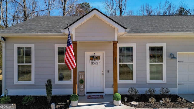 doorway to property featuring a shingled roof and an attached garage