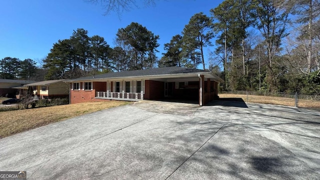 ranch-style house featuring a carport, covered porch, brick siding, and driveway