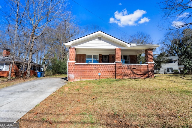 bungalow-style home with covered porch, a front yard, and brick siding