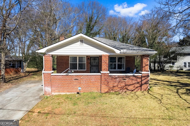 bungalow-style house with covered porch, a chimney, a front lawn, and brick siding