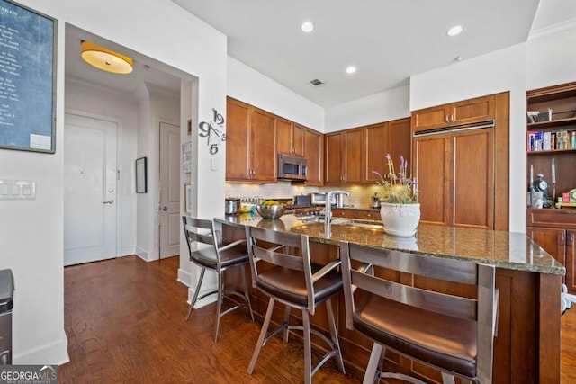 3630 Peachtree Rd NE Unit 1809, Atlanta, GA 30326 - kitchen with stainless steel microwave, dark stone countertops, dark wood-type flooring, paneled built in fridge, and decorative backsplash