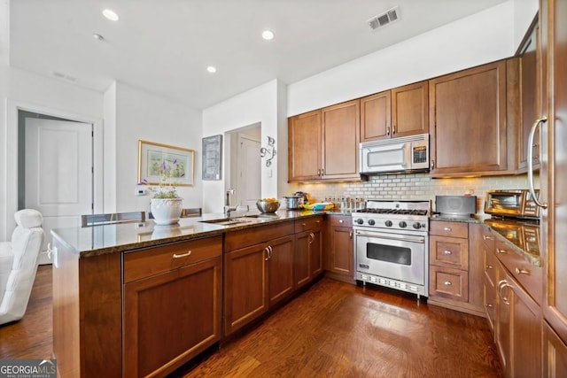 3630 Peachtree Rd NE Unit 1809, Atlanta, GA 30326 - kitchen with stainless steel appliances, a peninsula, brown cabinetry, dark stone counters, and recessed lighting