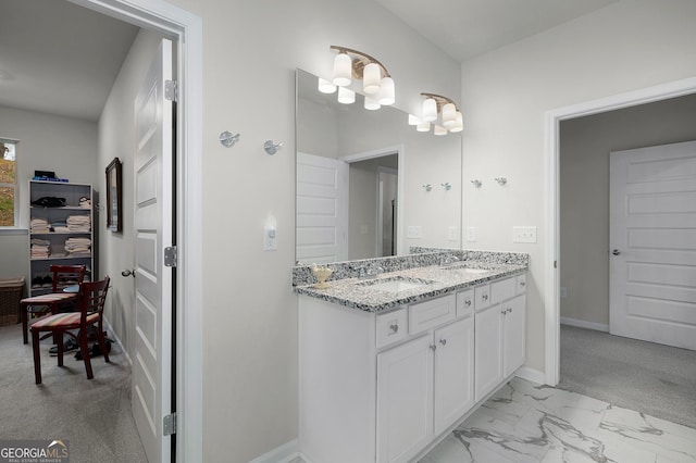 bathroom featuring double vanity, marble finish floor, baseboards, and a sink