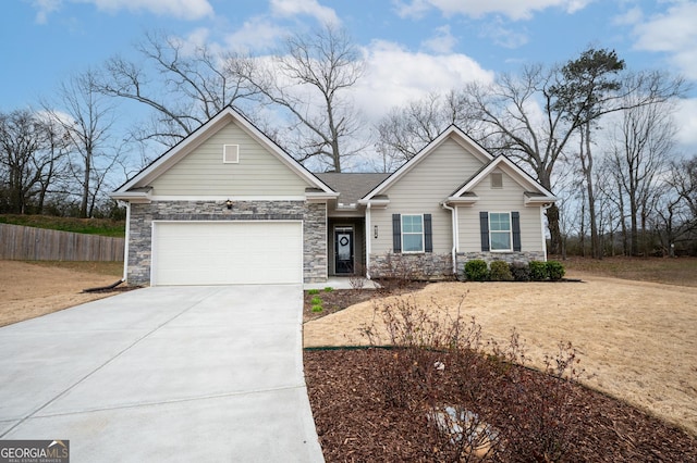 view of front of property featuring a garage, stone siding, driveway, and fence