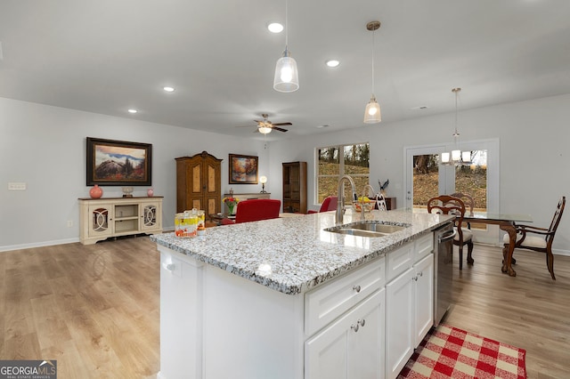 kitchen featuring a center island with sink, open floor plan, a sink, white cabinetry, and stainless steel dishwasher