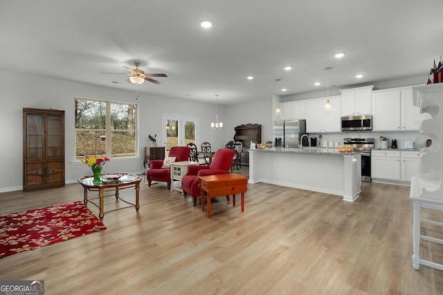 living area with light wood-type flooring, ceiling fan, baseboards, and recessed lighting