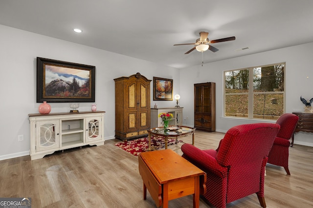 living area with baseboards, ceiling fan, and light wood-style floors