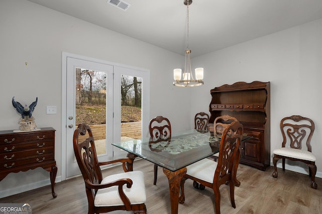 dining area with light wood-style flooring, visible vents, and an inviting chandelier